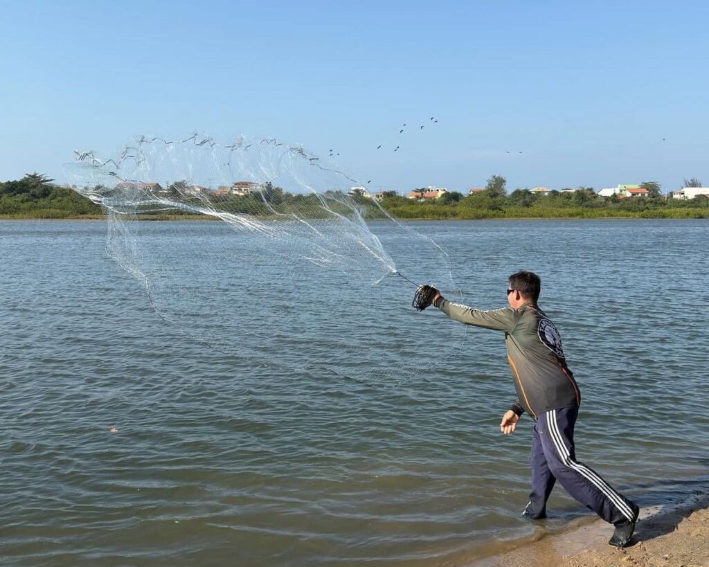 A Prefeitura de Maricá, por meio da Secretaria de Pesca, promoveu mais uma etapa do Circuito de Pesca de Maricá. Realizada no bairro Ponte Preta, a pescaria foi especial por ser disputada com o uso de tarrafa na lagoa do bairro, diferentemente das etapas no mar, que usam molinetes. Dezenas de pessoas acompanharam a competição, que aconteceu ao lado da ponte do bairro. “O Circuito de Pesca valoriza a nossa história, a nossa cultura que vem da pesca artesanal. Aqui na Ponte Preta estamos resgatando a lagoa, a prática da pescaria artesanal e certamente haverá outros eventos do tipo no bairro. É uma ação que reúne os moradores da região, os pescadores, e que faz girar a economia local” ressaltou o secretário de Pesca Xandi de Bambuí. Outra missão que o Circuito de Pesca tem é levar educação ambiental para os amantes da pescaria e moradores das orlas de Maricá que, muitas vezes, acabam prejudicando o meio ambiente por falta de conhecimento. “Essa planta que cresce na beira da lagoa e que temos muita aqui, hoje, é chamada de capim peteque. Quem não conhece pensa que é um indicativo de que a água está suja, mas não tem nada a ver. É uma planta que parece uma grama e que serve de abrigo e berçário para os peixes, atuando diretamente na reprodução. São informações que são repassadas para as pessoas para que nos ajudem a preservar”, finalizou Xandi de Bambuí. Durante o evento, em campanha de educação ambiental, equipes da Somar realizaram a limpeza da orla e distribuíram sacolas biodegradáveis para que as pessoas colocassem seu lixo e providenciassem o descarte em local adequado. “Sou pescador desde que nasci, há 40 anos. Aprendi com meu pai, que aprendeu com o pai dele. Então é uma tradição que a gente precisa preservar porque é a nossa raiz aqui em Maricá. Preservar a lagoa faz parte disso”, disse o pescador Charles do Amparo, que competiu no Circuito.