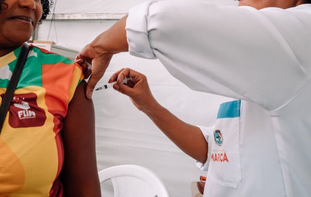 A Prefeitura de Maricá, por meio da Secretaria de Saúde, vai disponibilizar serviços de vacinação e práticas integrativas e complementares de saúde (PICS) na Festa Literária Internacional de Maricá (FLIM), que ocorre entre os dias 05 e 14/09 na orla do Parque Nanci. O objetivo da iniciativa é aproximar os serviços preventivos da população, ampliando o acesso às vacinas previstas no Calendário Nacional e promovendo o bem-estar de forma integral. No evento, adolescentes poderão receber as vacinas contra Dengue, HPV e ACWY (meningite). Para os adultos, estarão disponíveis imunizantes contra Difteria e Tétano (DT), Tríplice Viral (sarampo, caxumba e rubéola), Febre Amarela e Hepatite B. Para receber as doses necessárias, é necessário apresentar documento de identidade com CPF e a caderneta de vacinação (caso tenha). O secretário de Saúde, Marcelo Velho, ressaltou que a vacinação na FLIM é uma oportunidade para unir entretenimento e prevenção de doenças. “O objetivo da iniciativa é ampliar o acesso da população à prevenção, oferecendo a oportunidade de atualização vacinal em um evento de grande alcance como a FLIM. Assim, conseguimos unir saúde, cultura e lazer em benefício de toda a população de Maricá”, garantiu. De acordo com a superintendente de Vigilância em Saúde, Daniella Bittencourt, a iniciativa reforça o compromisso do município em manter a população protegida. “Estar presente na FLIM é uma forma de aproximar ainda mais os serviços de saúde da população, incentivando a prevenção e garantindo mais segurança e tranquilidade para todos. A vacinação é uma ação que fortalece a proteção coletiva, com toda a segurança, por isso convocamos a população a se vacinar durante a FLIM”, acrescentou. Além da imunização, os visitantes poderão participar de atividades de promoção da saúde com as PICS, voltadas ao bem-estar físico e emocional, garantindo mais qualidade de vida durante e após o evento. FLIM celebra dez anos de escrevivências A Festa Literária Internacional de Maricá (FLIM) celebra a sua décima edição em 2025. Consolidada como uma das maiores celebrações literárias do país, terá como homenageada a escritora e moradora do município Conceição Evaristo. Além disso, serão mais de 100 autores locais e dezenas de escritores nacionais e internacionais em mesas de debates, lançamentos e encontros com o público durante as atividades do evento.